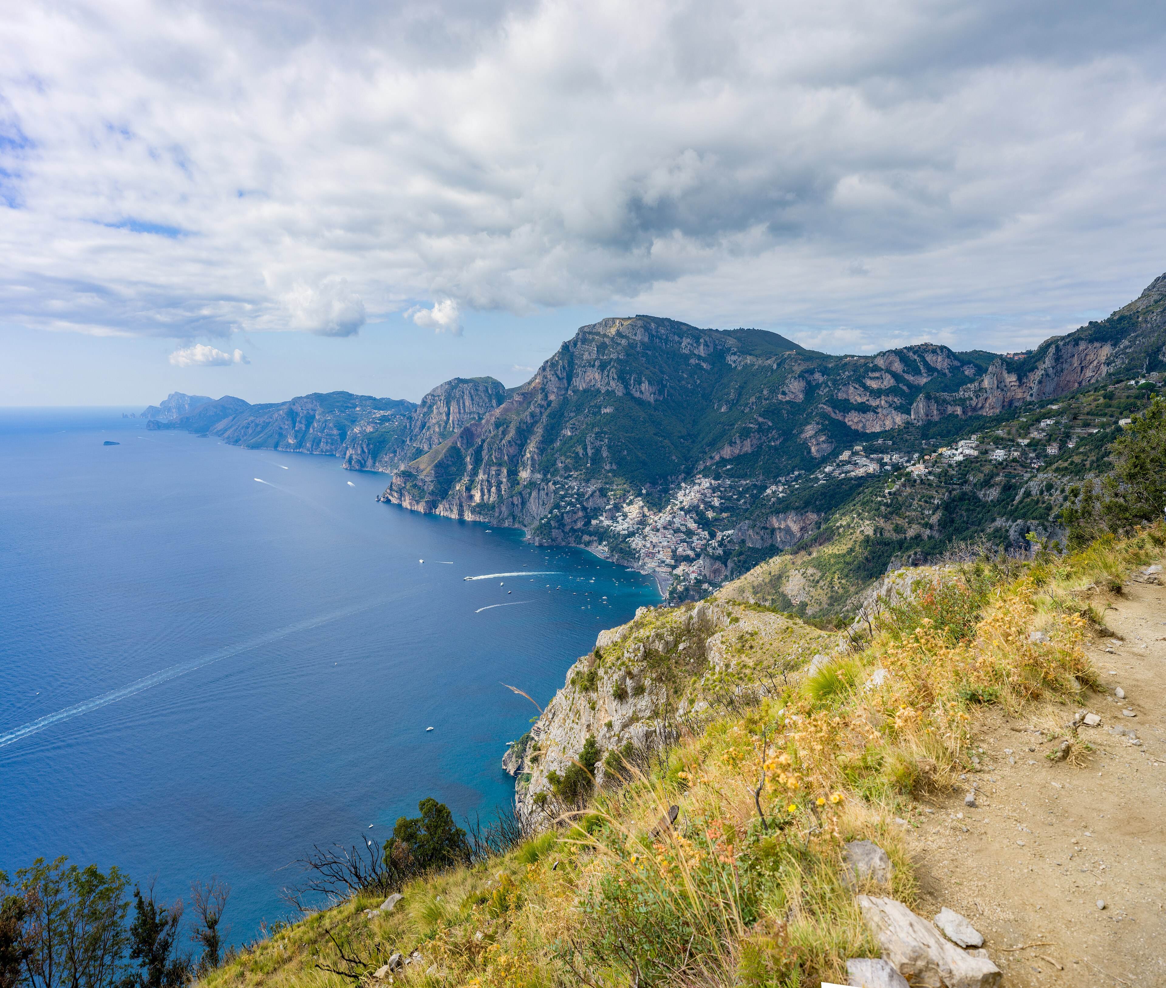 The dirt path running along a grassy ridge, with Positano and the coast far below